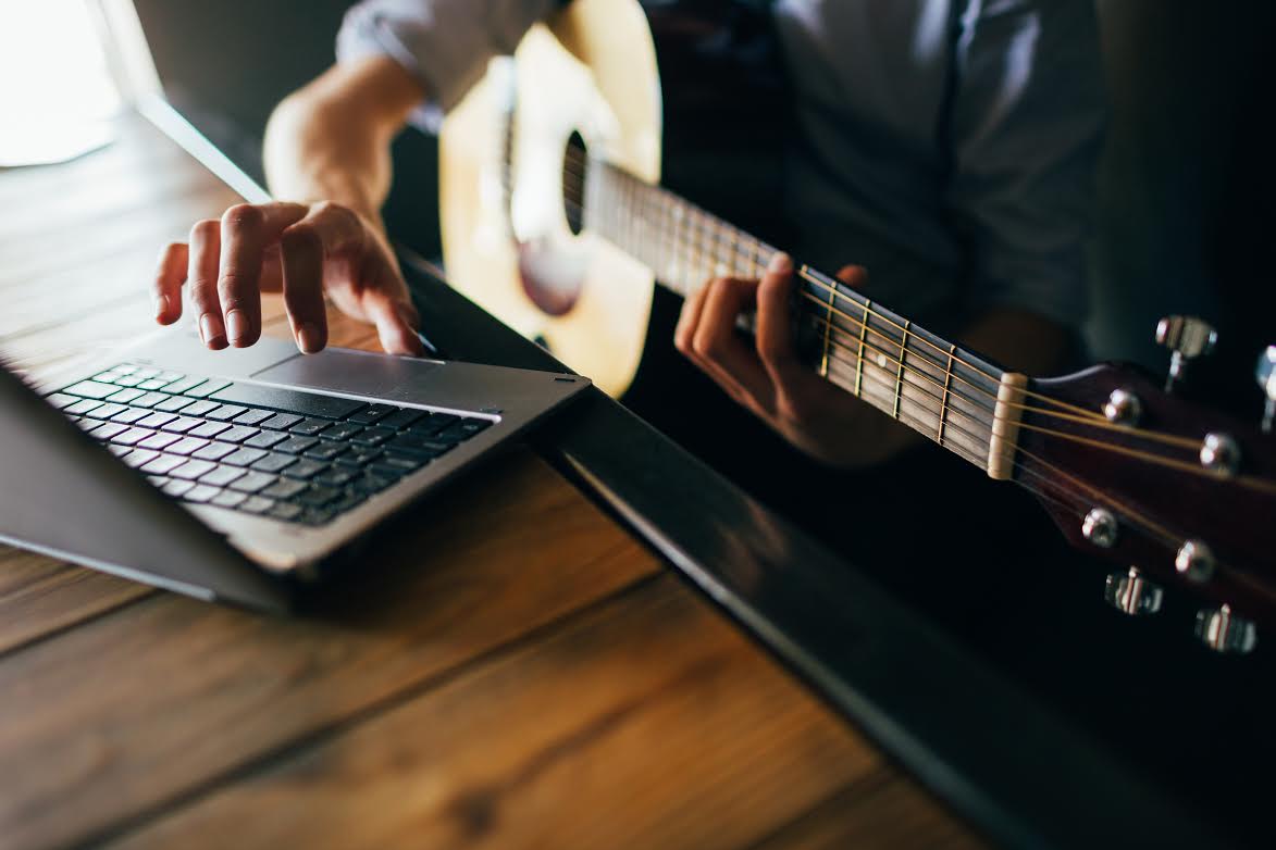 young man learns how to play guitar through the internet